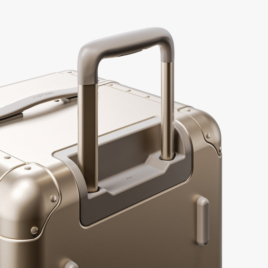 Champagne Gold | Extended luggage handle view of Aluminum Trunk in Champagne Gold