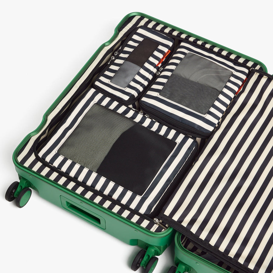 Set of Six / Poplin Stripe Black | Poplin Stripe Black compressible packing cubes neatly organized inside a Jungle Green open suitcase