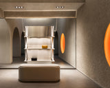 Minimalist display area inside the Monos Georgetown store, featuring brushed steel shelving framed by arched walls and glowing circular light features.