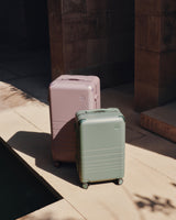 The Hybrid Trunk in Orchid and the Hybrid Carry-On in Mint, side by side in soft natural light.