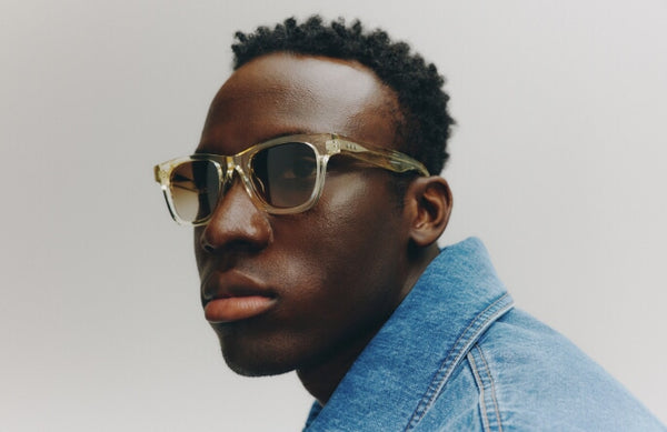 Man wearing sunglasses and a denim jacket against a plain background